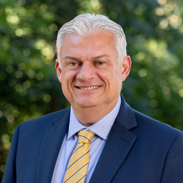 Jorge Ancona wearing a blue coat and yellow striped tie.